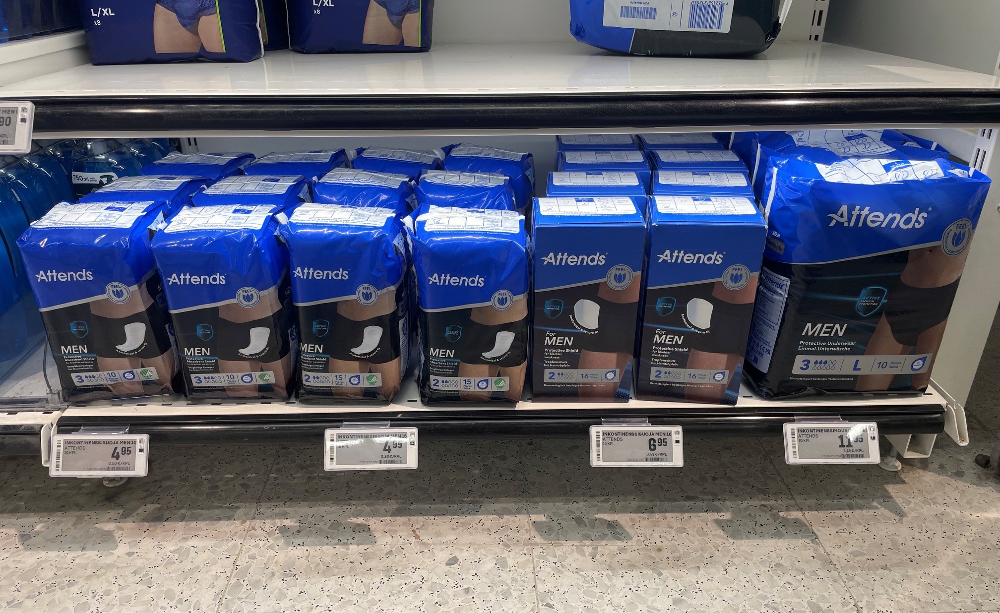 Miesten inkontinenssisuojia rivissä kaupan hyllyllä ja hinnat alla